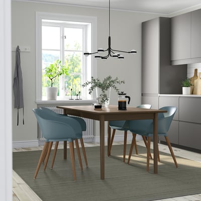 SKANSNÄS 4-seat dining set with brown table, grey-turquoise chairs, and extendable leaf. Set on green rug near window.