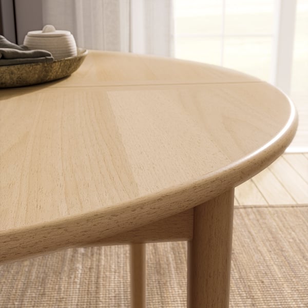 Light wood round dining table with extension leaf.