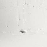 Water droplets drain from SKARPÖ armchairs seat hole, showcasing its self-draining feature.