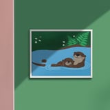 SKOGSDUVA poster shows a brown otter family swimming in blue water. Framed, displayed against a green wall. Size: medium.