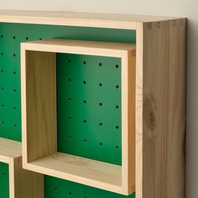 A SKOGSMOSAIK shelf with a green back and wooden frame, featuring moveable inner shelves for versatile storage.
