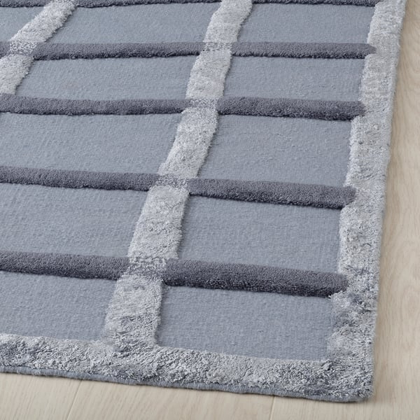 Abstract, woven rug with varying textures in neutral colors, showcasing high-quality craftsmanship and intricate design.
