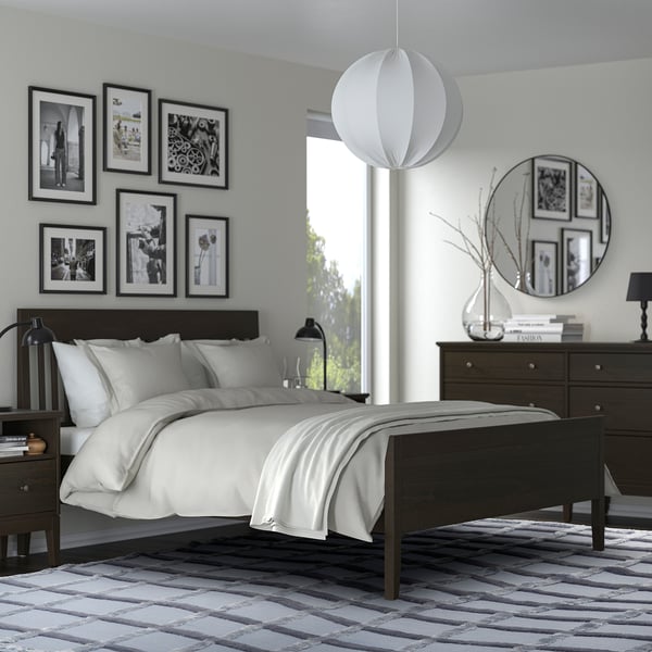 Modern bedroom with black & white decor, gray SKUGGSVINGEL rug, black bed & dresser, white lights.