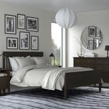 Modern bedroom with black & white decor, gray SKUGGSVINGEL rug, black bed & dresser, white lights.