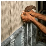 Close-up of hands weaving wool rug, using tapestry tool, showing intricate design.