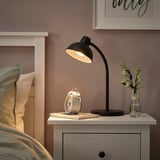 Modern bedroom with SKURUP lamp, alarm clock, and striped pillows.