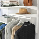 Closet with hangers, sweater storage, hat display on shelf.