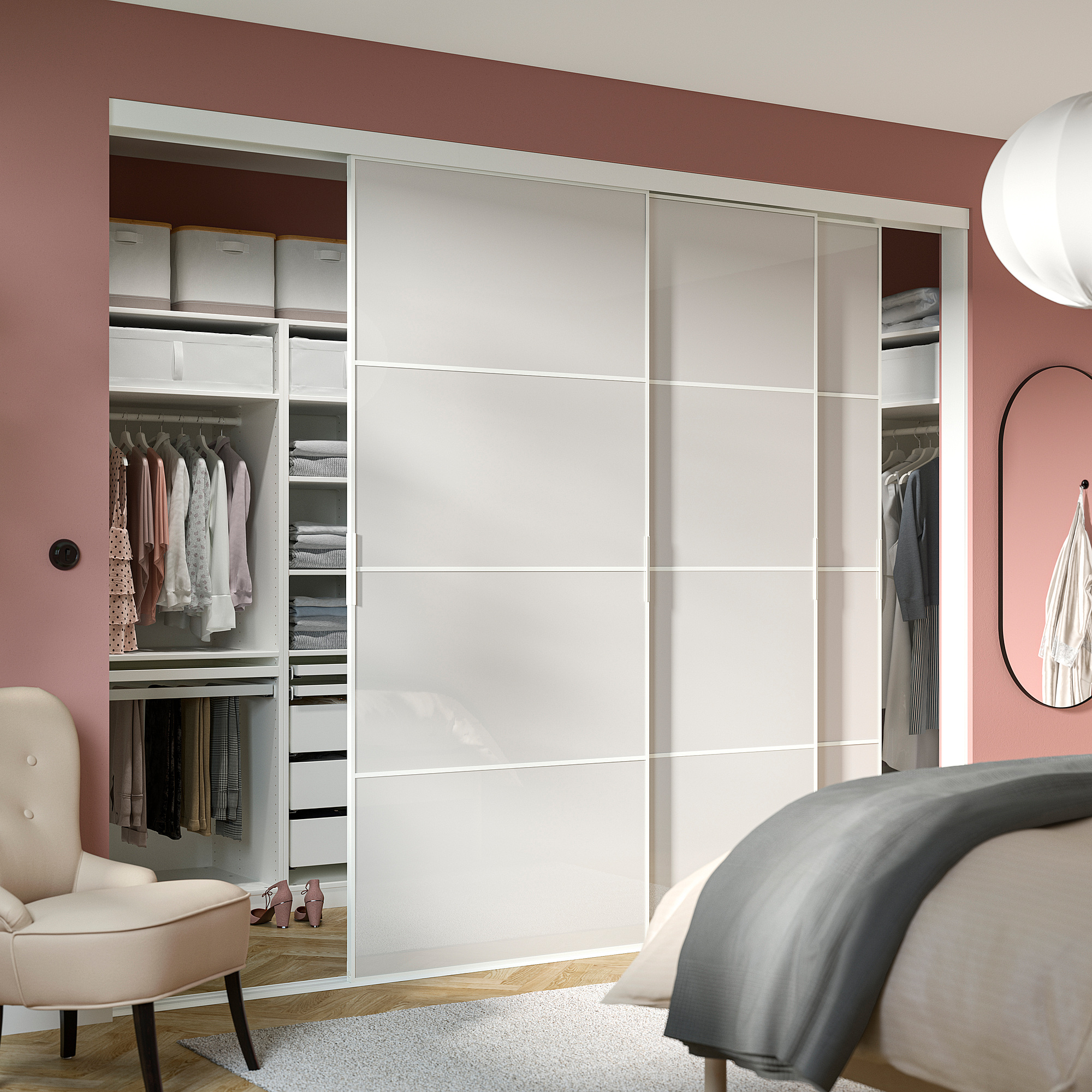 Modern bedroom with large SKYTTA wardrobe, white sliding doors, pink walls, organized clothes, beige chair, grey rug, bed, clock.