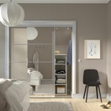 A modern bedroom with a large SKYTTA mirrored wardrobe and a black chair.