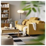 Modern living room with yellow SLATORP sofa, wooden coffee table, bookshelf, and floor lamp, creating a cozy and stylish space.