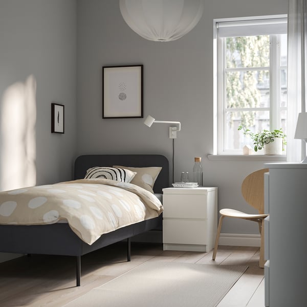 Minimalist bedroom with SLATTUM bed, black headboard, pendant light, sheer curtains, and polka dot duvet.