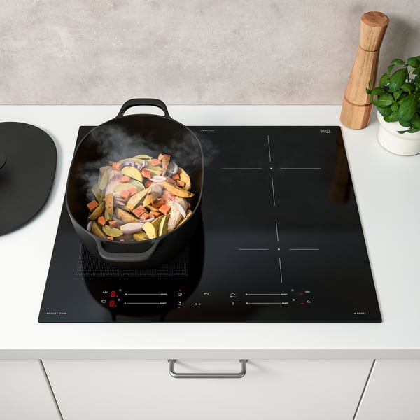 Modern kitchen scene with a steaming pan on an induction stove, showing the power boost and bridge functions.