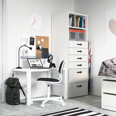 A modern students bedroom with a white SMÅSTAD desk, black chair, and gray storage unit featuring drawers and shelves.