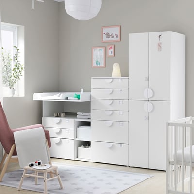 Nursery with white SMÅSTAD furniture, red armchair, crib, highchair, gray rug, wall art.