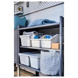A gray metal shelf with white storage bins and folded textiles.