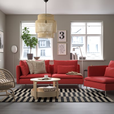 Modern living room with red SÖDERHAMN sofa, matching chair, black-and-white rug, and layered pendant lamp.