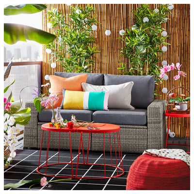Modern lounge: grey sofa, red tables, plants, bamboo fence.