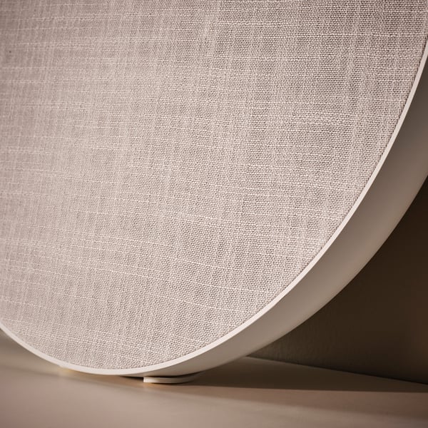Close-up of SOLSKYDD speaker, white, curved design, fabric cover.