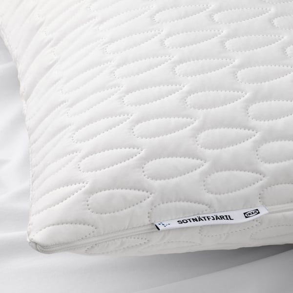 Close-up of a plush, white pillow protector, quilted with a wavy pattern, displaying branding at one corner.