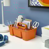 Orange desk organizer with office supplies, lamp, headphones, and frame. Made from recycled plastic.