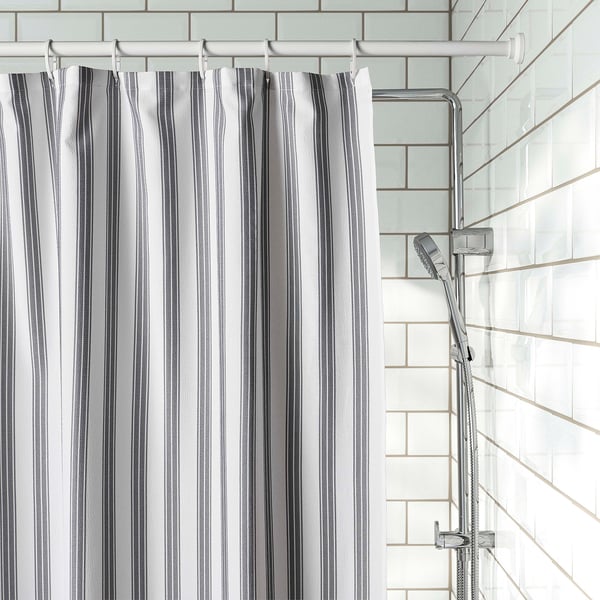 Striped shower curtain hangs near a tiled wall with a modern chrome shower head.