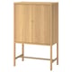 A wooden cabinet named STOCKHOLM 2025 in a light oak finish. It has two doors with a brass key and adjustable feet for stability.