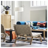 Modern living room with light wood easy chair, woven linen seat, blue sofa, and striped rug.