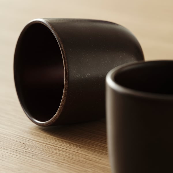 Dark stoneware mugs, subtle speckles, rustic design, placed on wooden surface.