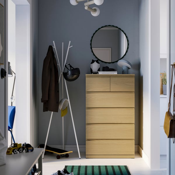 Modern bedroom with brown STORKLINTA chest, mirror, coat stand & skateboard.