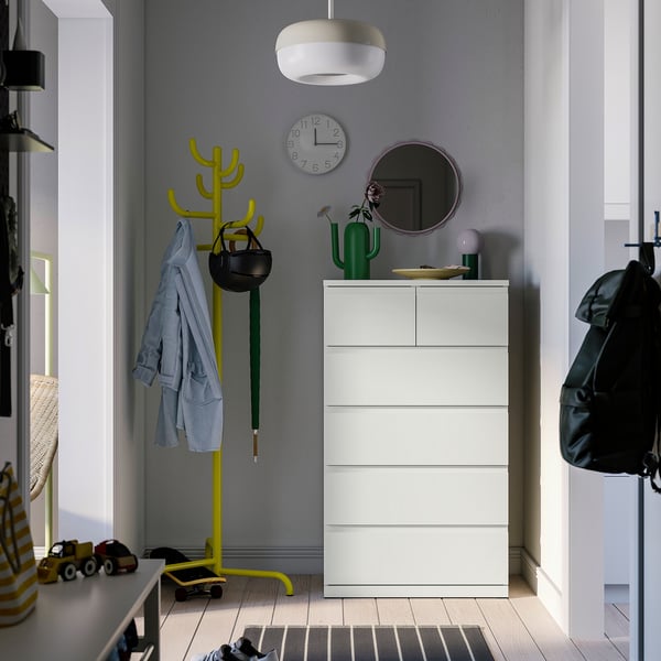 White STORKLINTA chest of drawers with 6 drawers, between coat rack & door, decorated.