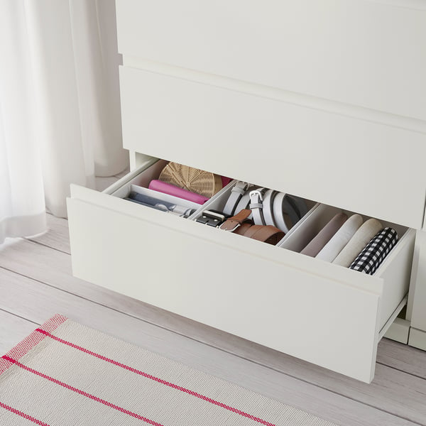 White dresser with six drawers, organised accessories.