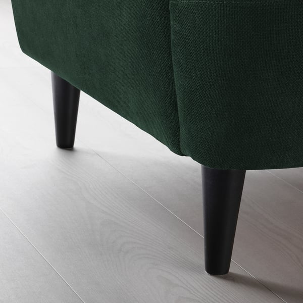 Dark green upholstered chair with sleek black legs on floor.