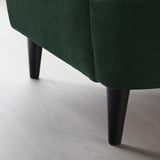 Dark green upholstered chair with sleek black legs on floor.