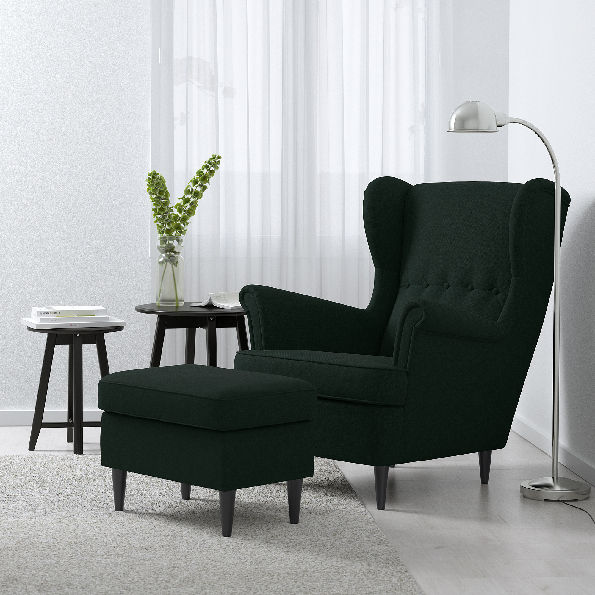 Modern living room with dark green, wingback STRANDMON chair & ottoman. Sleek design, lamp, side table, and plant. Large chair, tall lamp.