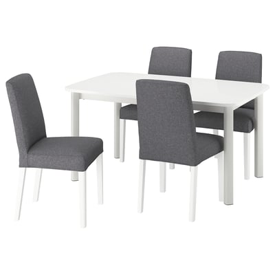 A white STRANDTORP extendable dining table and four grey fabric chairs. The table has sleek legs and the chairs have high backs and white legs.