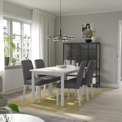 Modern dining room with STRANDTORP extendable table and chairs, on a yellow rug.