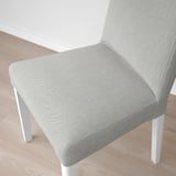 Modern upholstered chair with clean lines and cushioned seat on wooden floor. Seat and backrest feature stylish, textured fabric.