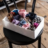 Box of colorful rolled socks on a black stool.