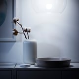 Modern bathroom with white ribbed vase holding cotton plant, round gray sink, and stylish pendant light overhead.