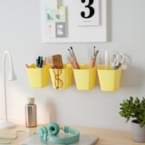 Bright desk setup with yellow organizers, pens, headphones, plant, and lamp.