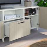 White tv stand with open drawer revealing gaming console and controllers. Shelves hold decorative items and storage boxes.
