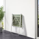 White and green outdoor foldable table on balcony, leans against white wall. Perfect for small spaces.