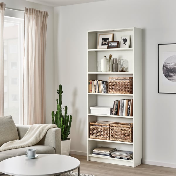 Living room with TÄTING rattan basket in billy bookcase, near sofa, table, and cactus.