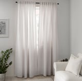Modern minimalist room with sheer TIBAST curtains, white armchair, and plant.