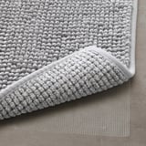 Close-up of a soft, textured gray bath mat with a non-slip mesh underside, ensuring safety and quick drying.