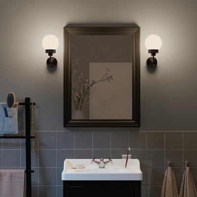 Modern bathroom with TOFTBYN mirror, wall lamps, sink, toothbrushes, and toiletries.