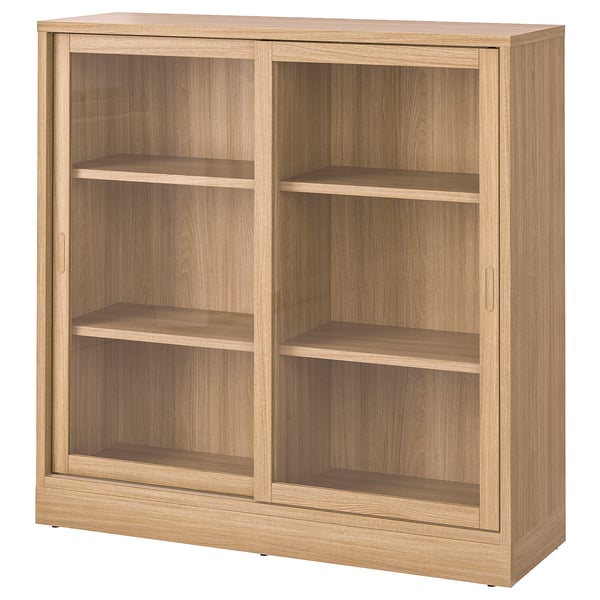 A TONSTAD wooden cabinet in oak color. It sliding glass doors, three shelves, and a classic design.