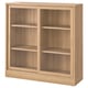 A TONSTAD wooden cabinet in oak color. It sliding glass doors, three shelves, and a classic design.