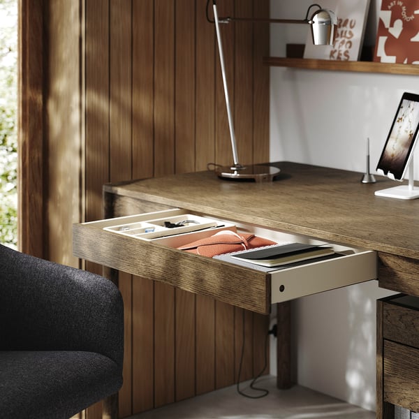 Wooden desk with open drawer, lamp, and tablet holder, showcasing organized workspace setup.