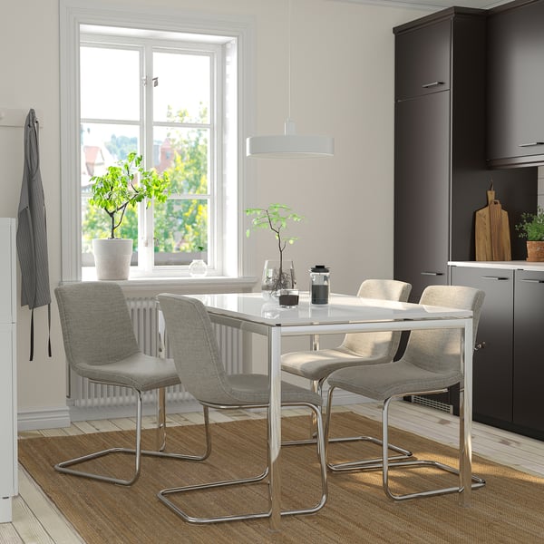 Modern dining set with 4 gray chairs and white table, positioned near a window, creating a cozy and well-lit space.